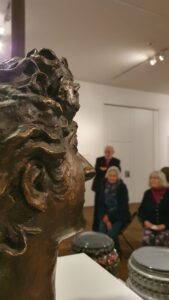 Mitglieder des Kunstvereins bei der Führung durch die Ausstellung im Schloss Gottorf mit Dr. Borges. Im Vordergrund ein Bronzekopf, Selbstportrait von Willumsen