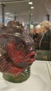 Mitglieder des Kunstvereins bei der Führung durch die Ausstellung im Schloss Gottorf. Im Vordergrund "Seehase/Lumpfisch" Fayence