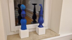 Vernissage Farbe, Form & Fantasie Bernd Wilms Zwei blaue Skulpturen im Fenster mit Spiegelung