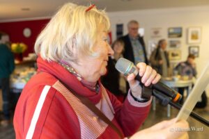 Annegret Vahle liest ein Gedicht und hält ein Mikrofon