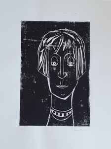 Holzschnitt eine weiblichen Kopfes mit Pagenkopffrisur. Die Farbe des Hintergrunds ist schwarz, der Kopf weiß.