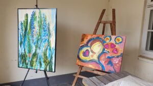 Zwei Acrylbilder, eines in Blautönen und eines in Rottönen auf Staffeleien