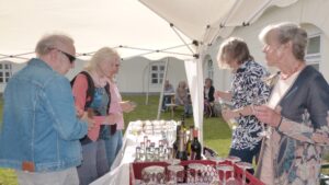 Vier Frauen und ein Mann an einem Getränketisch.