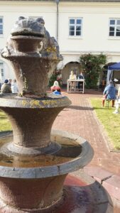 Ein dreistöckiger Brunnen vor dem weißen Verwaltungsgebäude im Innenhof.