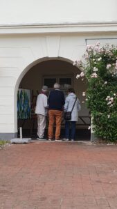 Eine Frau und zwei Männer bei der Betrachtung von Bildern.