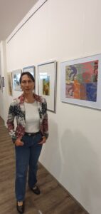 Eine Frau vor einem bunten Holzschnitt von Karin Palisaar.