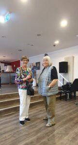 Karin Palisaar und ein Gast blicken lächelnd in die Kamera.