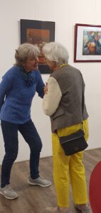 Zwie Frauen im angeregten Gespräch vor zwei Bildern von Elke Schady.