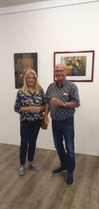 Eine Frau und ein Mann vor Bildern von Elke Schady lächeln in die Kamera.