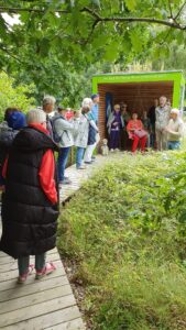 Arten Eden 2025 (10) Foto: M. Roos Eine Gruppe von Besuchern am Pavillon, der nach dem kleinen Prinzen benannt ist. Zum Pavillon fürt ein Holzsteg.