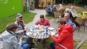 Arten Eden 2025 (15) Foto: M. Roos Gäste sitzen rund um Teaktische und unterhalten sich bei Kaffee und Kuchen.