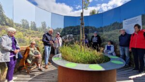 Arten Eden 2025 (24) Foto: H. Hoppe Eine Gruppe von Besuchern stehen in einem runden Pavillon, ehemals eine Klärgrube. Das Rund ist mit Fotoprints gestaltet und man hat die Illusion in eine Heidelandschaft zu schauen.