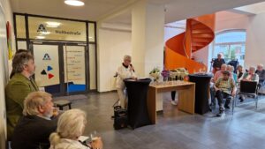 Inke Asmussen hält die Begrüßungsrede. Sie hält ein Mikrofon.