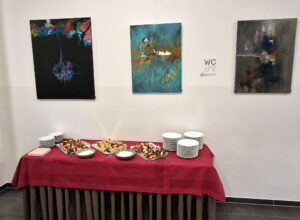 Drei abstrakte Acrylgemälde. Von links nach rechts in schwarz mit bunten Einsprengen, in Blautönen und in Erdtönen mit Blau.