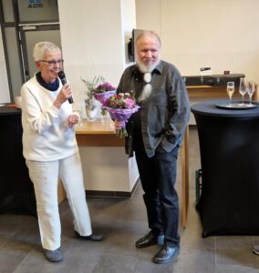 Inke Asmussen rechts übergibt Bernd Wilm einen Blumenstrauß.