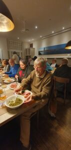 Mitglieder des Kunstvereins sitzen am Tisch und essen Grünkohl.