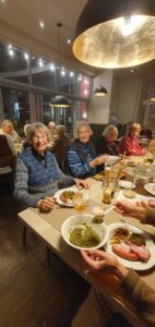 Mitglieder des Kunstvereins sitzen am Tisch und essen Grünkohl.