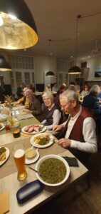 Mitglieder des Kunstvereins sitzen am Tisch und essen Grünkohl.