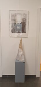 Monotypie mit Skulptur aus Granit im Vordergrund