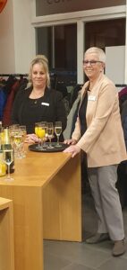 Inke Asmussen vor einem Tablett mit Sekt und Orangensaft, daneben eine Servicekraft.