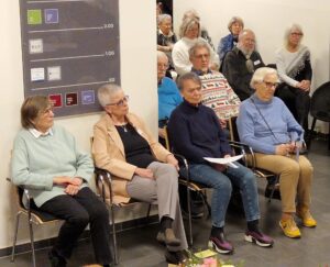 Gäste der Vernissage sitzend im Foyer des Quartier 36.