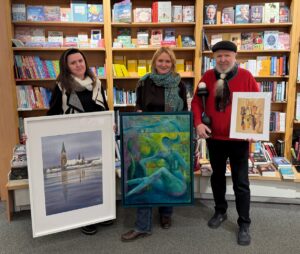 Zwei Frauen und ein Mann stehen mit ihren Bildern vor einer Bücherwand.