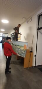 Zwei Männer hängen Bilder auf.