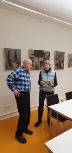 Der Künstler und die Laudatorin vor Bildern.