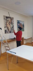 Bernd Wilms justiert ein Gemälde an der Wand.