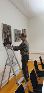 Ein Helfer justiert ein Bild an der Wand mit Wasserwage.