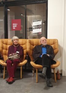 Claus Vahle sitzt in einm großen safrangelben Sessel, daneben eine Frau.