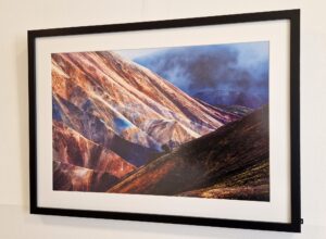 Ein Foto aus der Ausstellung zeigt eine Gebirgslandschaft in Kupfertönen vor dunklem Himmel.