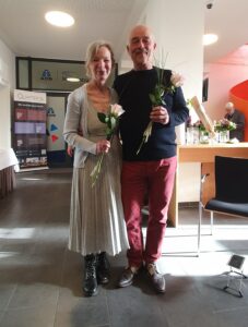 Susanne und Martin Jung mit je einer Rose in der Hand, lächeln in die Kamera.
